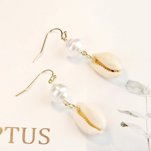 Detail of bohemian gold hook earrings with white pearl and natural seashell drop
