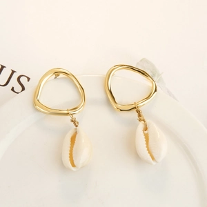 Macro shot of gold geometric earrings with natural white shells and intricate wire wrap