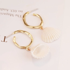 Detail of bohemian gold hoop earrings featuring natural white fan-shaped shell pendants