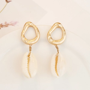 Detailed view of Bohemian shell earrings with gold wire wrapping on a ceramic tray