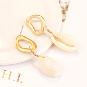 Detail of bohemian gold-plated hoop earrings with natural white seashell pendants
