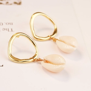 Detail of bohemian gold spiral earrings with natural white conch shell pendants