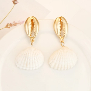 Detail of bohemian shell earrings with golden cowrie top and white scallop pendant