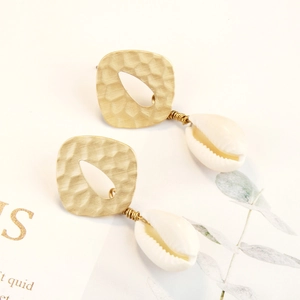 Detail of bohemian gold hammered metal earrings with natural white seashell pendants