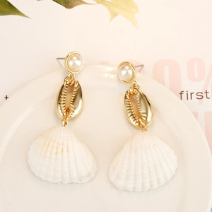 Detail showing golden alloy shell and natural white scallop drop earrings on a tray