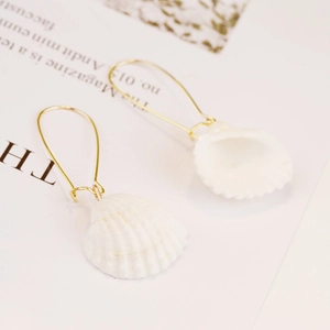 Detailed macro view of natural seashell stud earrings with elegant golden hooks