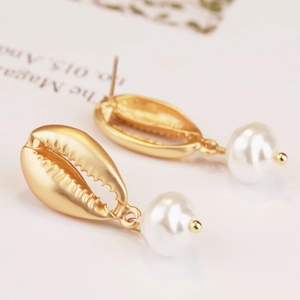 Detail of matte gold shell earrings with hanging pearls in a vintage bohemian style