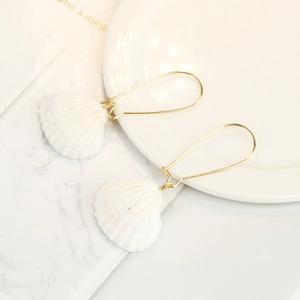 Detail of bohemian shell earrings featuring natural white texture and gold hooks