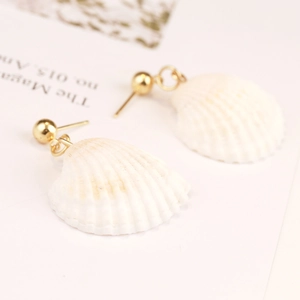 Detailed close-up of bohemian shell earrings with natural white fans and gold studs