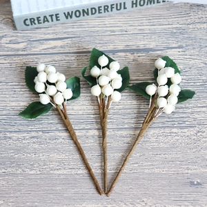 Three pieces of decorative white berries with green leaves and realistic stems on wooden surface