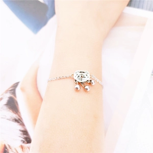 Detail of silver titanium steel bracelet with fortune lock charm and bells on wrist