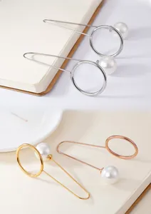 Close-up of elegant U-shaped metal pins with glossy pearls in gold and silver finishes