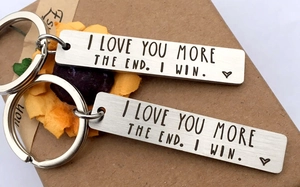 Detail of two stainless steel keychains engraved with I LOVE YOU MORE THE END I WIN