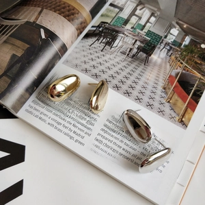 Detail of silver and gold teardrop studs on a fashion magazine background