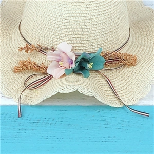 Women's summer straw sun hat with floral decoration and ribbon bow for beach holidays