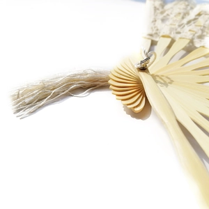Detail of vintage bamboo lace folding fan with intricate embroidery and cream tassel