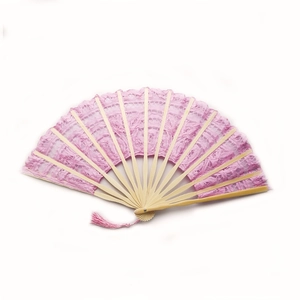 Detail of pink lace folding fan with intricate patterns and a matching silk tassel