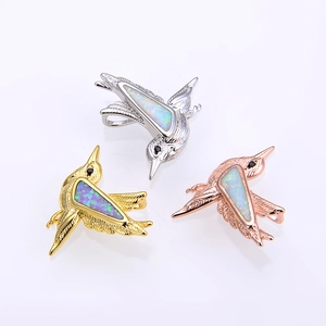 Detailed macro shot of hummingbird pendants in gold silver and rose gold opal settings