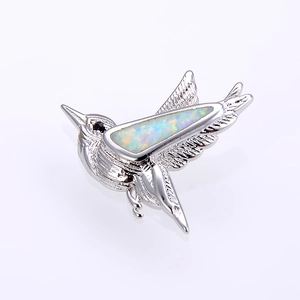 Macro detail of bird pendant with iridescent opal inlay and silver-tone metal textures