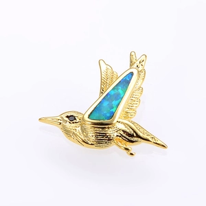 Detailed view of bird pendant with gold plating and blue-green opal stone wings