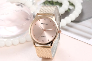 Détail de la montre rose doré avec index en cristal et bracelet en maille métallique