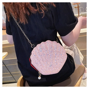 Close-up of pink sequined shell-shaped crossbody bag with pearl charm and gold chain