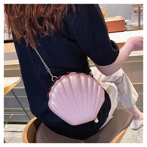 Pink shell shaped crossbody bag with pearlescent finish and elegant gold chain strap