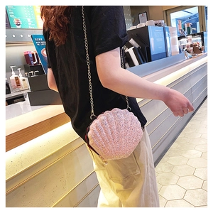Detailed view of pink shell-shaped crossbody bag with glitter finish and gold chain