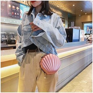 Detailed close-up of pink shell-shaped crossbody bag with gold chain and pearl zipper