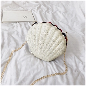 Detail of a creamy white mini shell bag with silver sequins, gold chain and pearl accent
