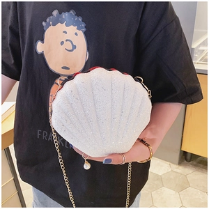 Detailed view of shell-shaped handbag with glitter finish and gold chain strap