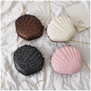 Flat lay of mini glitter seashell crossbody bags with gold chains and pearl zippers