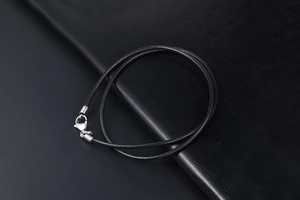 Detailed view of black waxed linen cord necklace featuring a silver lobster clasp closure