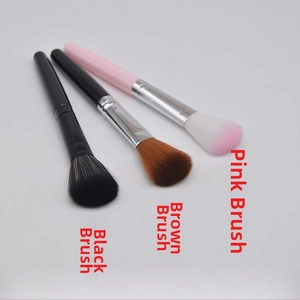 Detailed shot of three makeup brushes with black, brown, and pink bristles in parallel setup