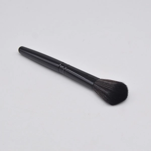 Detail view of professional black handle blush brush on a light grey background