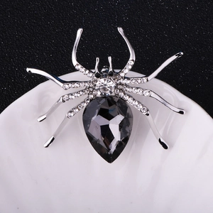 Detail of a sparkling crystal spider brooch featuring a large pear-cut dark grey gemstone