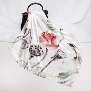 Detail of silk-like scarf featuring pink lotus ink painting draped on a black handbag