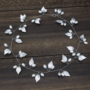 Close-up of handmade silver leaf headband with pearls on vintage wood background