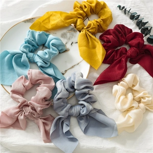 Silk satin scrunchies with long bows in various colors displayed on marble tray