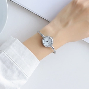 Detail of silver twisted cable bracelet watch featuring a white dial and quartz movement