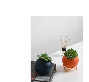 Detail of Morandi ceramic succulent pots with a minimalist gold metal stand on a white desk