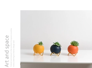Detail of three colorful Morandi ceramic succulent pots with golden metal tripods