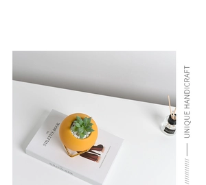 Detail of yellow matte ceramic succulent pot with elegant golden metal triangular stand