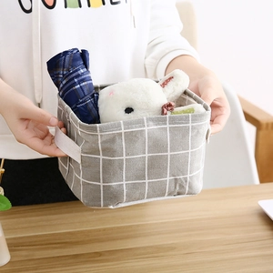 Gray checkered cotton linen storage basket with handles shown in person's hands