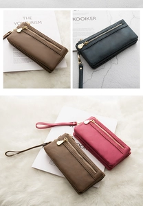 Three long PU leather wristlet wallets in brown, navy and rose pink on a magazine