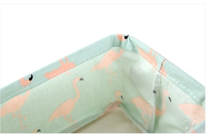 Close-up of mint green cotton linen storage basket with pink flamingo pattern and neat stitching