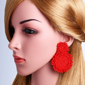 Detailed view of bohemian red beaded hoop earrings worn by a model on a blue background