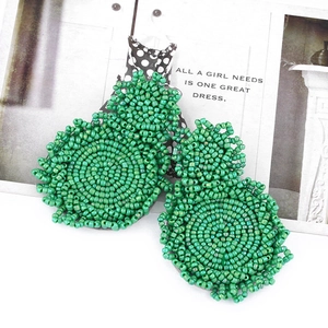 Macro detail of handmade green beaded boho earrings with layered round disk design