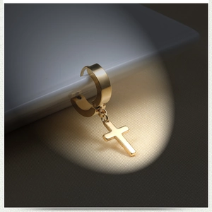 Macro shot of polished gold cross drop earring with a glossy metallic finish