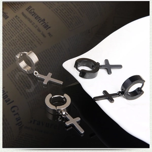 Macro view of silver and black stainless steel cross drop earrings on decorative paper